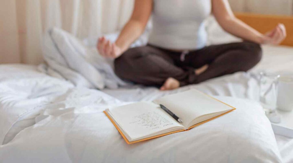 Woman Meditating and Journaling on Bed